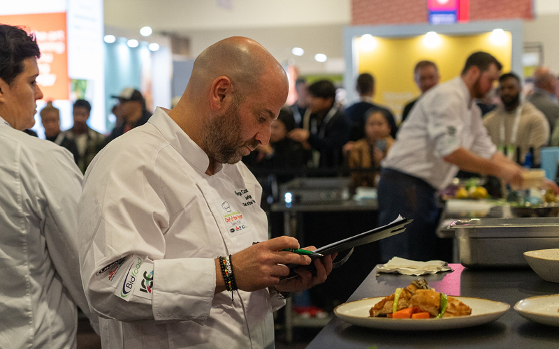 Chef in a white coat with a tablet at a culinary event at chef of the year