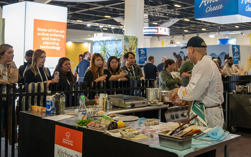 Chef at "Kitchen 3" station preparing food during a cooking demonstration at an event at chef of the year