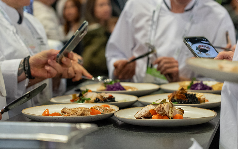 Group of chefs taking photos of gourmet dishes on a table at chef of the year