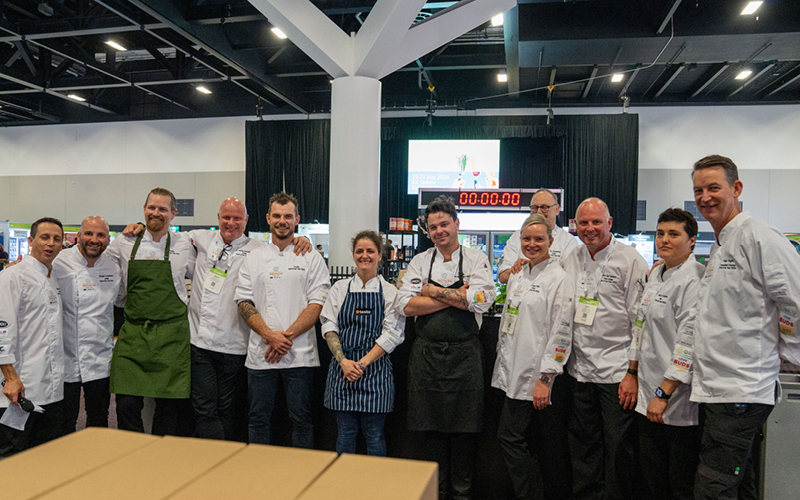 Group of people in chef jackets at a cooking event.