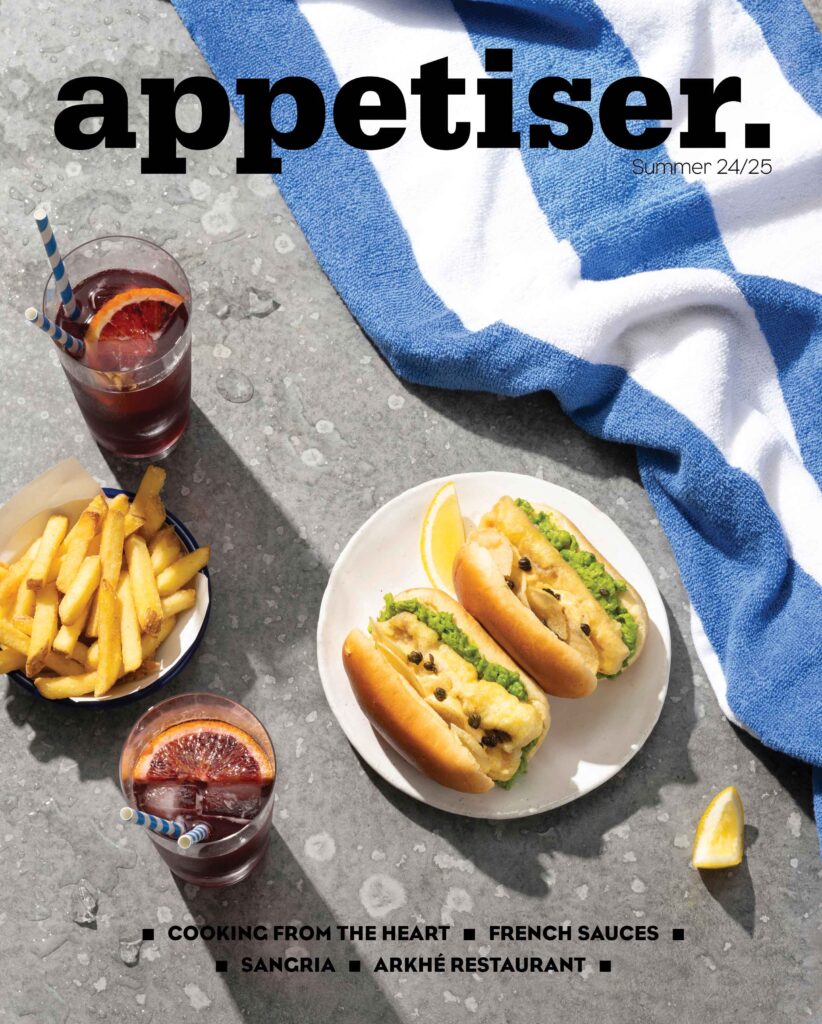 Two Sea Dogs sit next to refreshing cocktails poolside, evoking a relaxed summer vibe.