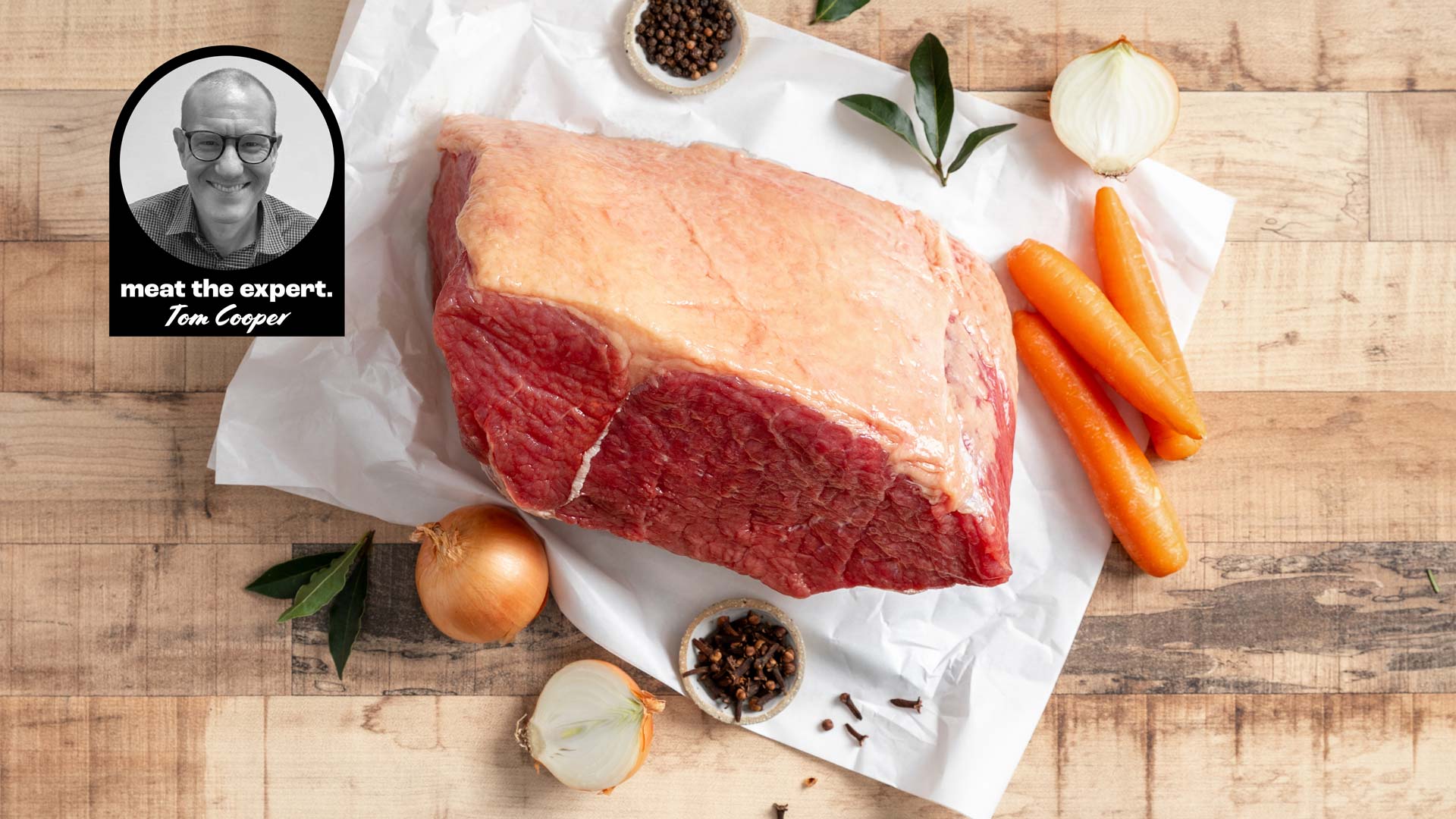 Raw corned beef silverside on butcher’s paper with carrots, onions, bay leaves, cloves and peppercorns, alongside a portrait of meat expert Tom Cooper.