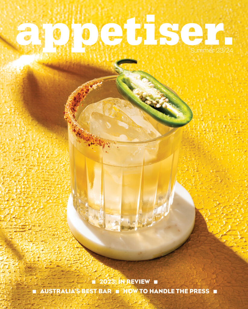 Bidfood Australias appetiser 2023 year in review magazine includes australias best bar and how to handle the press. The magazine frontpage image features a dusted rim cocktail topped with half a green jalapeño on a vivid canary yellow table cloth.