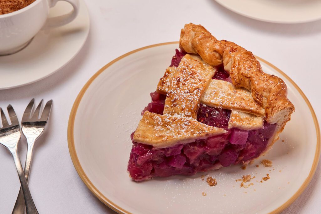 Two bowls of laksa curry topped with fresh herbs, lime, bok choy, and chilies, are beautifully presented with chopsticks and porcelain spoons on a dark textured surface